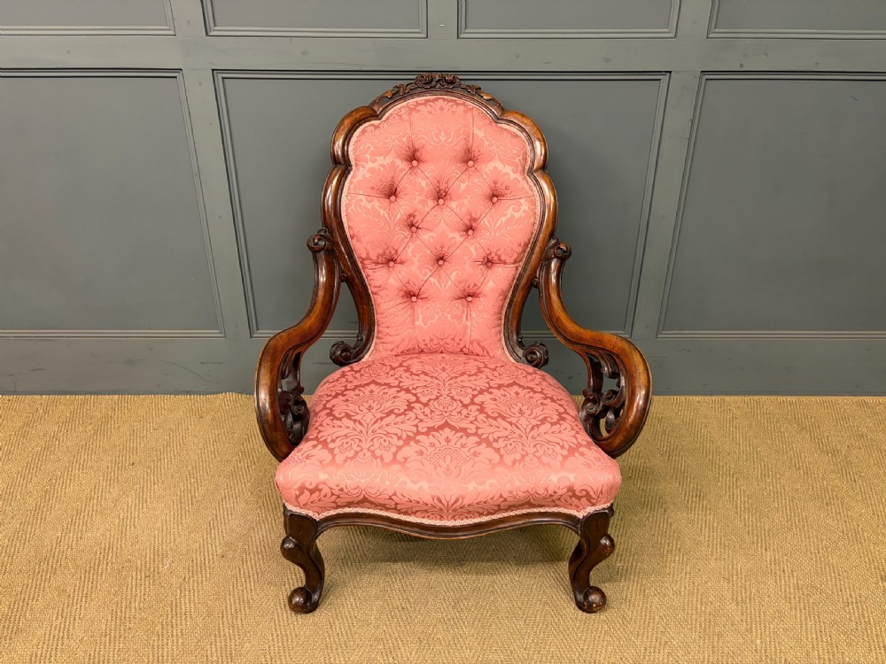 A pair of mid-Victorian carved walnut nursing chairs upholstered in buttoned pink damask fabric with cabriole legs. View III