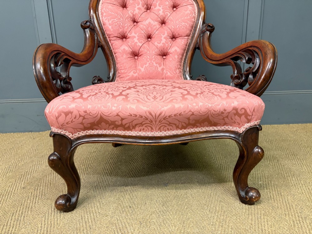 A pair of mid-Victorian carved walnut nursing chairs upholstered in buttoned pink damask fabric with cabriole legs. View V