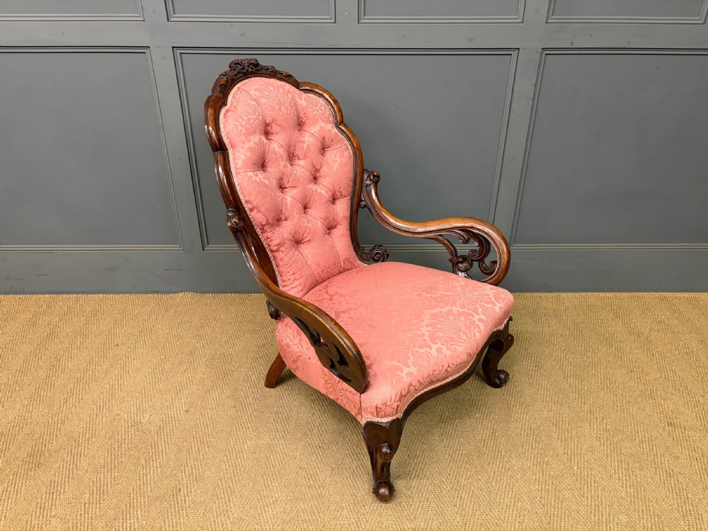 A pair of mid-Victorian carved walnut nursing chairs upholstered in buttoned pink damask fabric with cabriole legs. View VI