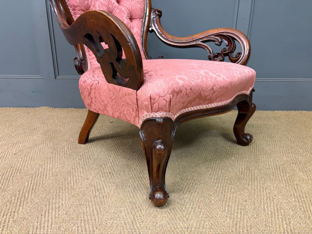 A pair of mid-Victorian carved walnut nursing chairs upholstered in buttoned pink damask fabric with cabriole legs. View X