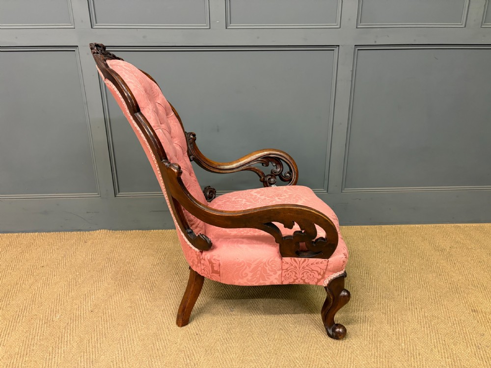 A pair of mid-Victorian carved walnut nursing chairs upholstered in buttoned pink damask fabric with cabriole legs. View XI