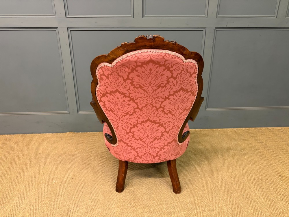 A pair of mid-Victorian carved walnut nursing chairs upholstered in buttoned pink damask fabric with cabriole legs. View XII