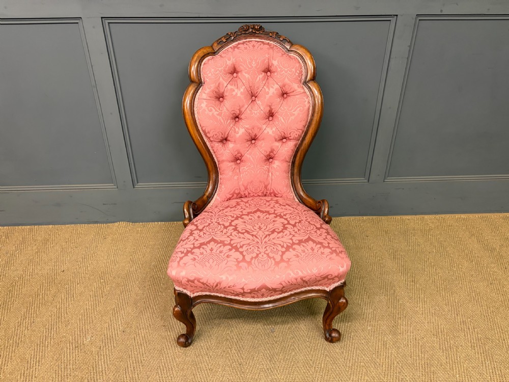 A pair of mid-Victorian carved walnut nursing chairs upholstered in buttoned pink damask fabric with cabriole legs. View XIII