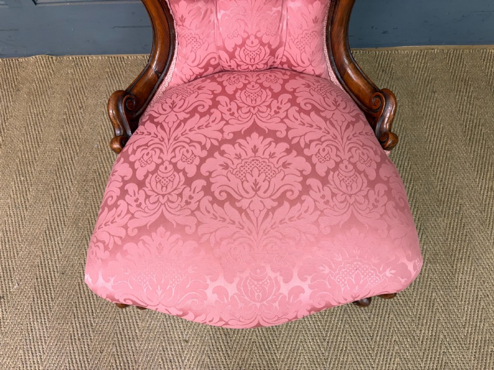 A pair of mid-Victorian carved walnut nursing chairs upholstered in buttoned pink damask fabric with cabriole legs. View XIV