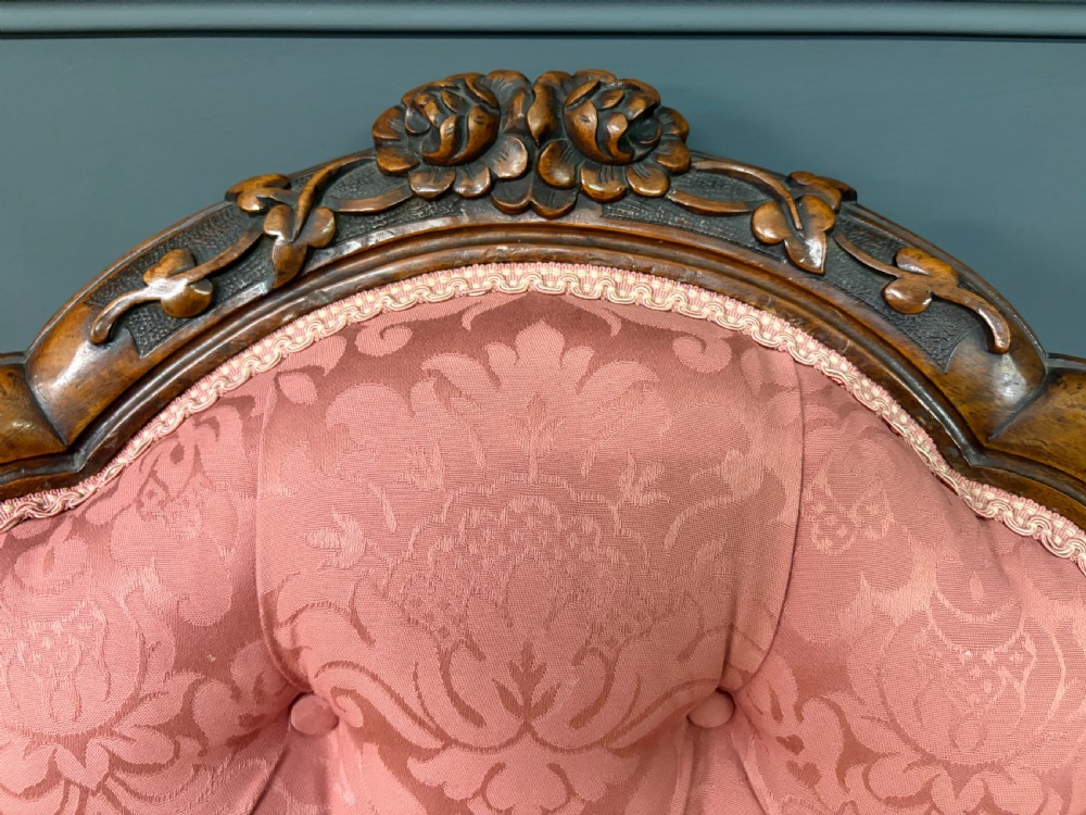 A pair of mid-Victorian carved walnut nursing chairs upholstered in buttoned pink damask fabric with cabriole legs. View XV