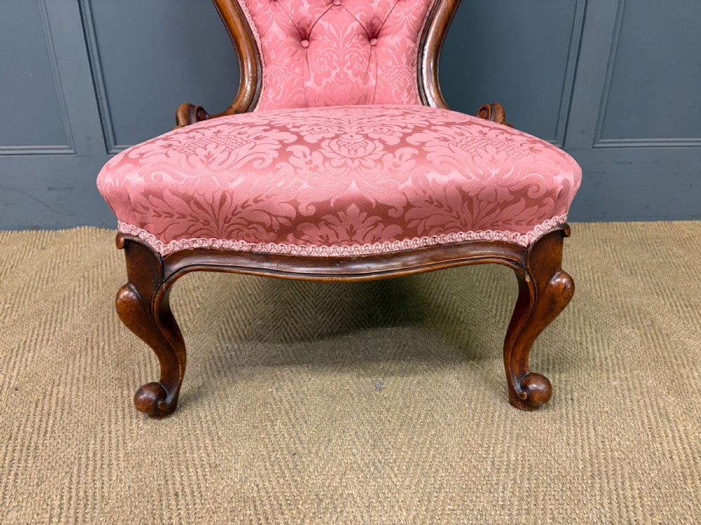 A pair of mid-Victorian carved walnut nursing chairs upholstered in buttoned pink damask fabric with cabriole legs. View XVI