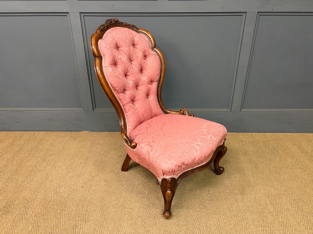 A pair of mid-Victorian carved walnut nursing chairs upholstered in buttoned pink damask fabric with cabriole legs. View XVII