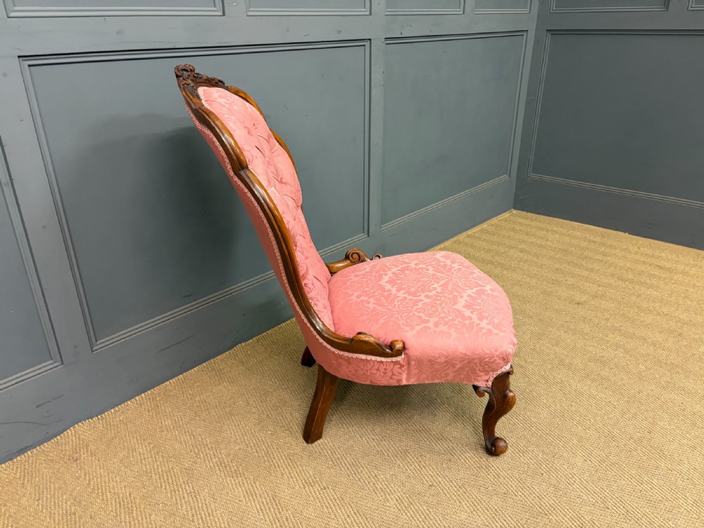 A pair of mid-Victorian carved walnut nursing chairs upholstered in buttoned pink damask fabric with cabriole legs. View XVIII