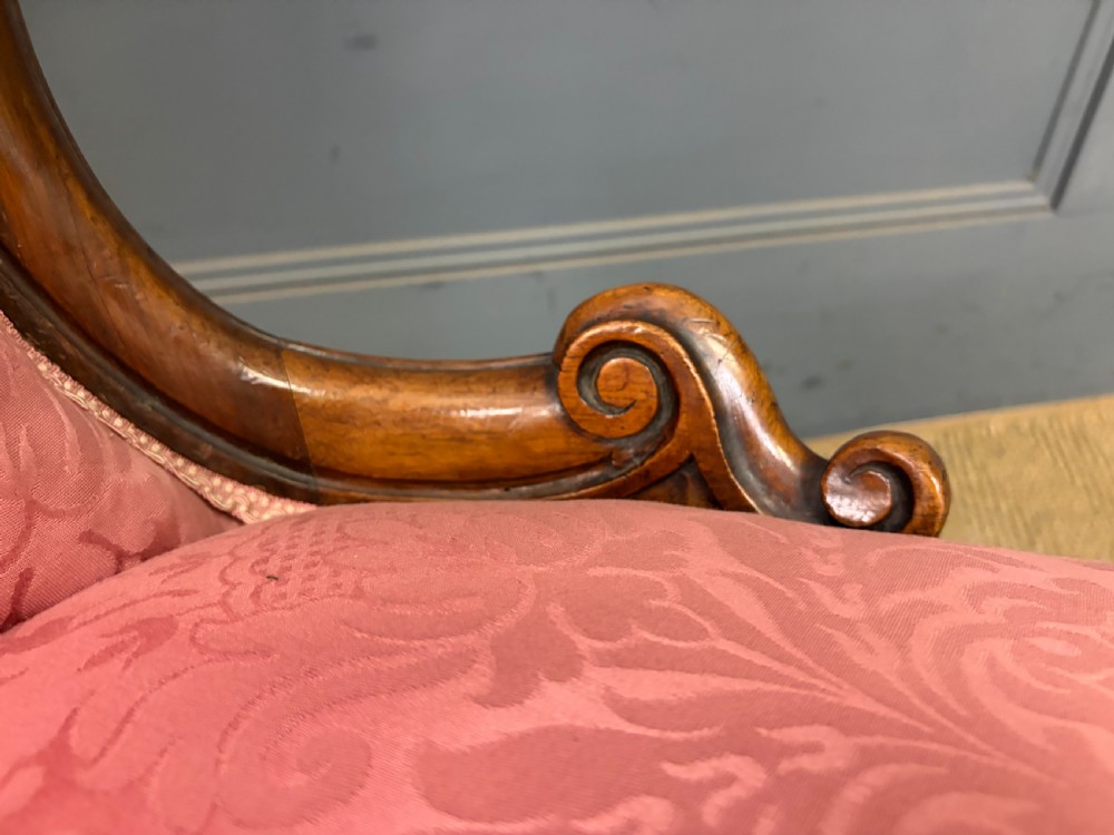 A pair of mid-Victorian carved walnut nursing chairs upholstered in buttoned pink damask fabric with cabriole legs. View XIX