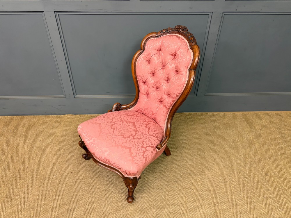 A pair of mid-Victorian carved walnut nursing chairs upholstered in buttoned pink damask fabric with cabriole legs. View XX