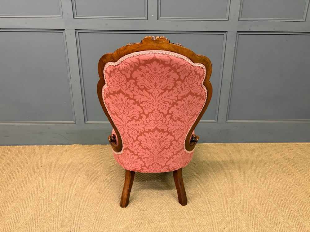A pair of mid-Victorian carved walnut nursing chairs upholstered in buttoned pink damask fabric with cabriole legs. View XXI