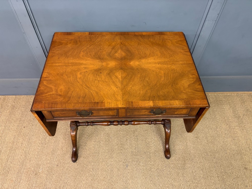 A burr walnut sofa table featuring twin drop leaves, two front drawers with brass handles, and double turned stretchers. View III