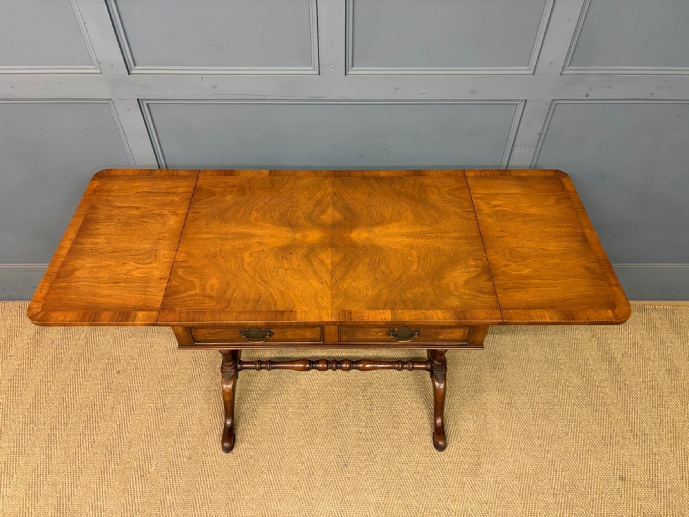 A burr walnut sofa table featuring twin drop leaves, two front drawers with brass handles, and double turned stretchers. View VII
