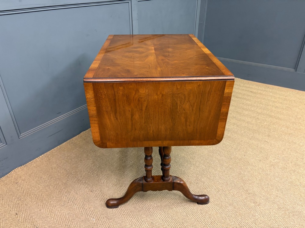 A burr walnut sofa table featuring twin drop leaves, two front drawers with brass handles, and double turned stretchers. View XI