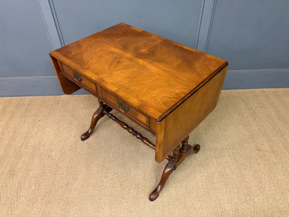 A burr walnut sofa table featuring twin drop leaves, two front drawers with brass handles, and double turned stretchers. View XIII