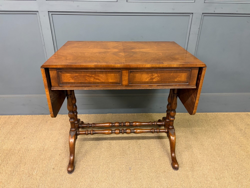 A burr walnut sofa table featuring twin drop leaves, two front drawers with brass handles, and double turned stretchers. View XIV