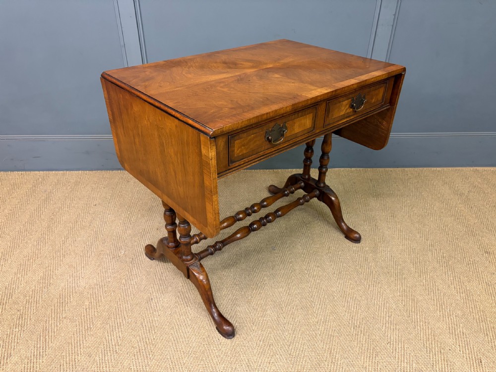 A burr walnut sofa table featuring twin drop leaves, two front drawers with brass handles, and double turned stretchers. View XV