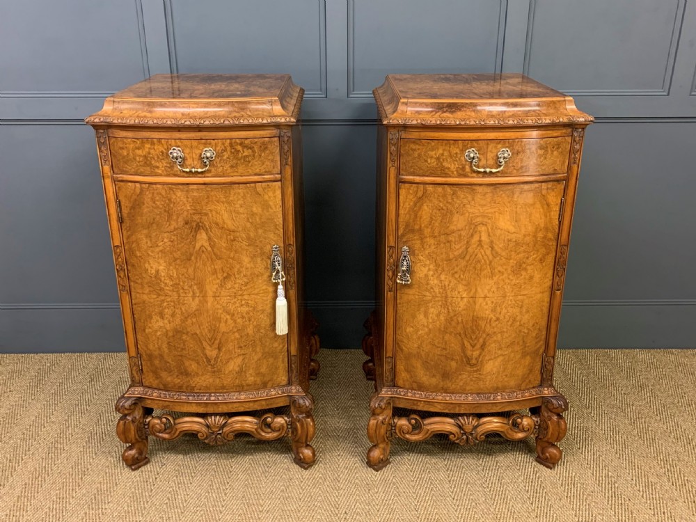 A pair of tall burr walnut pedestal cupboards featuring curved front doors, single top drawers with brass drop handles, and carved scroll feet. View II