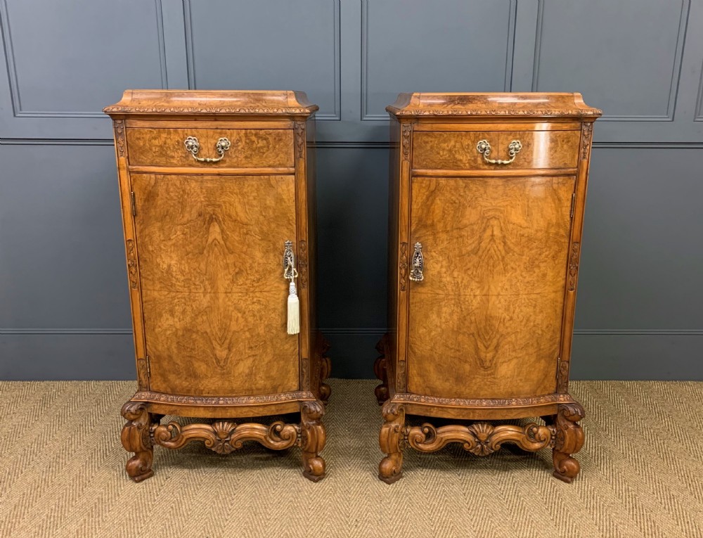 A pair of tall burr walnut pedestal cupboards featuring curved front doors, single top drawers with brass drop handles, and carved scroll feet. View III