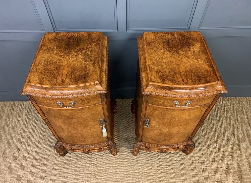 A pair of tall burr walnut pedestal cupboards featuring curved front doors, single top drawers with brass drop handles, and carved scroll feet. View IV
