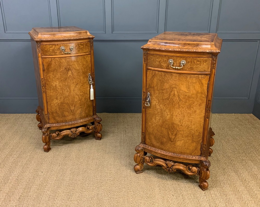 A pair of tall burr walnut pedestal cupboards featuring curved front doors, single top drawers with brass drop handles, and carved scroll feet. View VIII