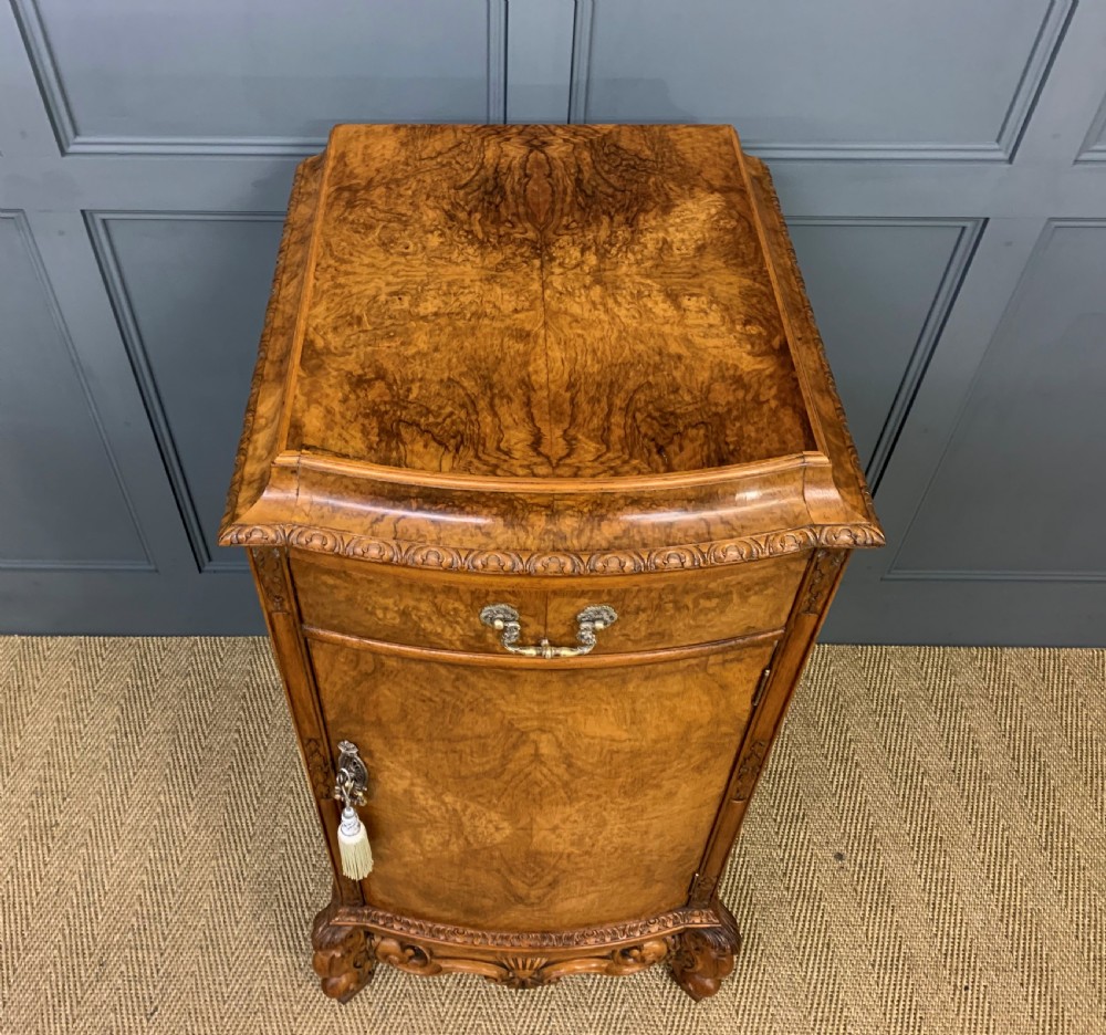 A pair of tall burr walnut pedestal cupboards featuring curved front doors, single top drawers with brass drop handles, and carved scroll feet. View XIV