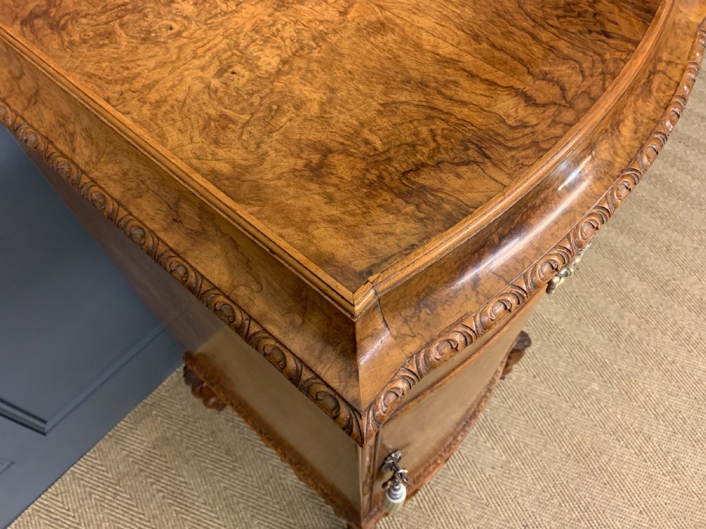 A pair of tall burr walnut pedestal cupboards featuring curved front doors, single top drawers with brass drop handles, and carved scroll feet. View XV