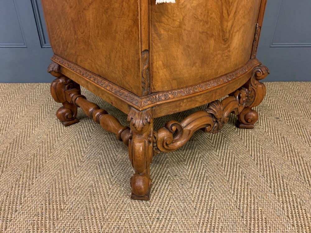 A pair of tall burr walnut pedestal cupboards featuring curved front doors, single top drawers with brass drop handles, and carved scroll feet. View XVII