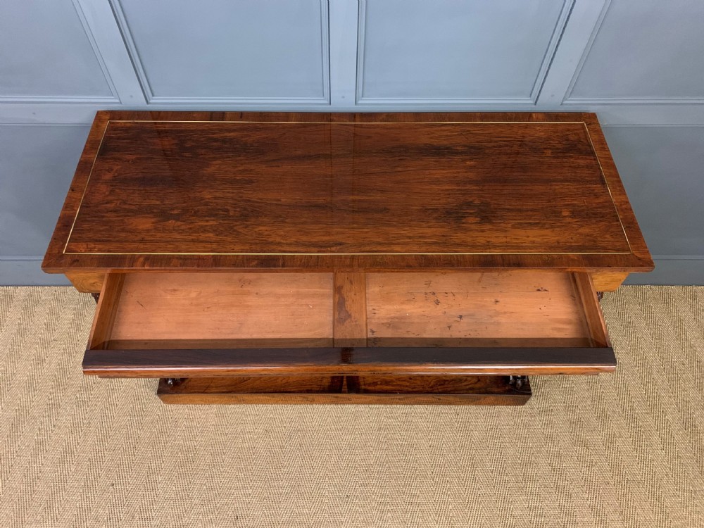 A dark Regency period rosewood side cabinet featuring two cupboard doors with gilded bronze trim and carved scroll supports on a plinth base. View VI