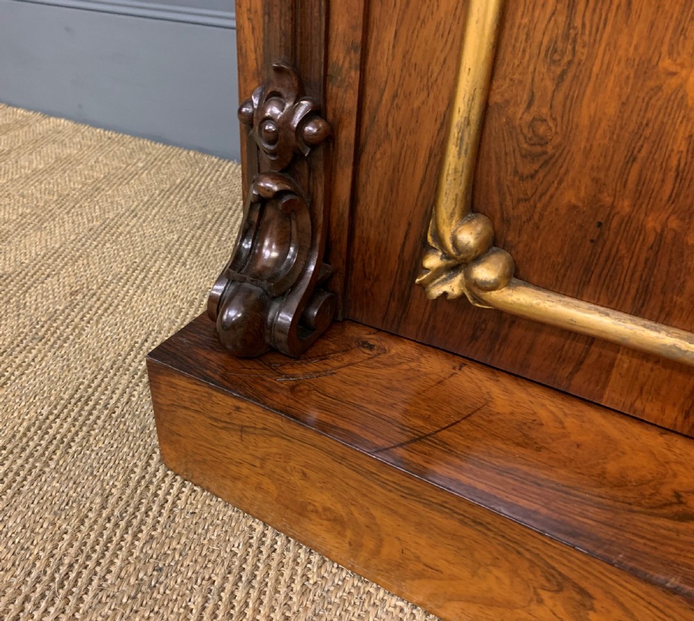 A dark Regency period rosewood side cabinet featuring two cupboard doors with gilded bronze trim and carved scroll supports on a plinth base. View XIII
