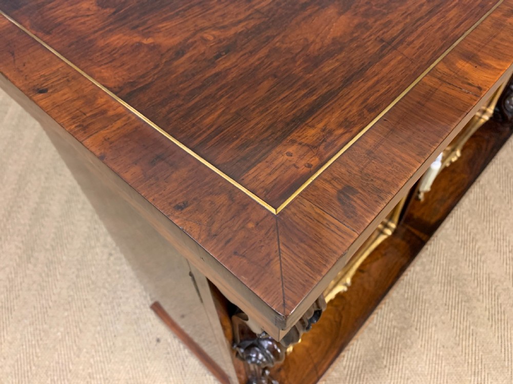 A dark Regency period rosewood side cabinet featuring two cupboard doors with gilded bronze trim and carved scroll supports on a plinth base. View XVI