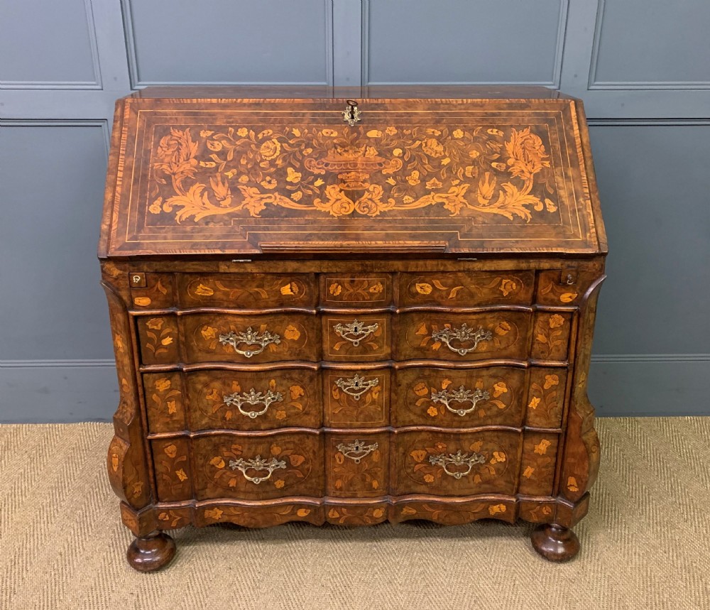 An 18th-century Dutch walnut bureau featuring detailed floral marquetry inlay across the slant-front lid and drawer fronts, accented with brass handles.