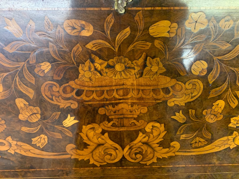 An 18th-century Dutch walnut bureau featuring detailed floral marquetry inlay across the slant-front lid and drawer fronts, accented with brass handles. View V