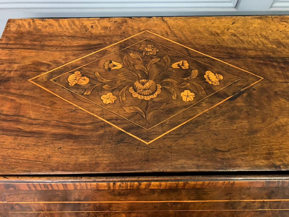 An 18th-century Dutch walnut bureau featuring detailed floral marquetry inlay across the slant-front lid and drawer fronts, accented with brass handles. View VI