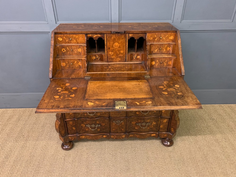 An 18th-century Dutch walnut bureau featuring detailed floral marquetry inlay across the slant-front lid and drawer fronts, accented with brass handles. View VII