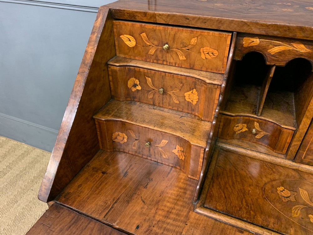 An 18th-century Dutch walnut bureau featuring detailed floral marquetry inlay across the slant-front lid and drawer fronts, accented with brass handles. View IX