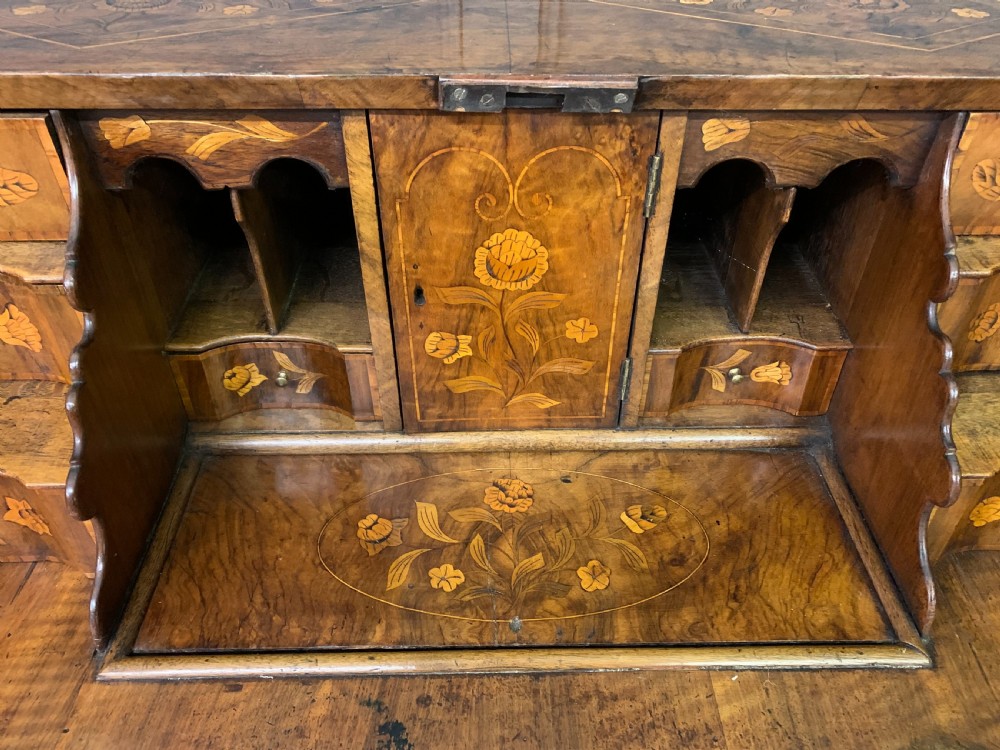 An 18th-century Dutch walnut bureau featuring detailed floral marquetry inlay across the slant-front lid and drawer fronts, accented with brass handles. View X