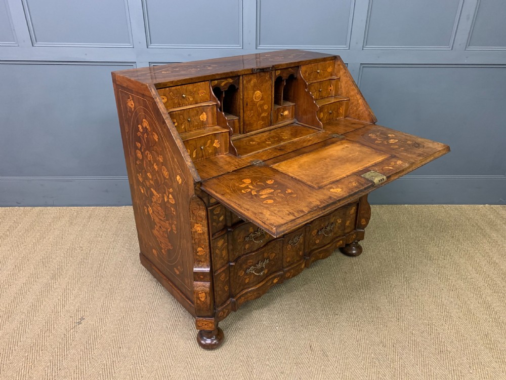 An 18th-century Dutch walnut bureau featuring detailed floral marquetry inlay across the slant-front lid and drawer fronts, accented with brass handles. View XVI