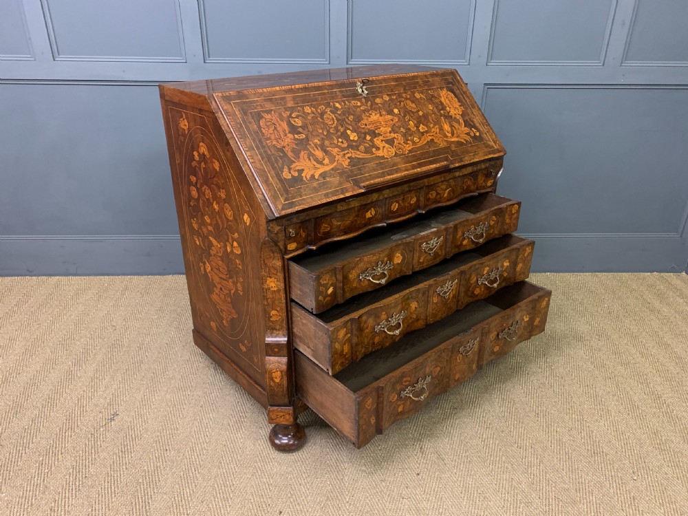 An 18th-century Dutch walnut bureau featuring detailed floral marquetry inlay across the slant-front lid and drawer fronts, accented with brass handles. View XVII