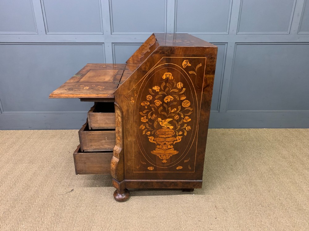 An 18th-century Dutch walnut bureau featuring detailed floral marquetry inlay across the slant-front lid and drawer fronts, accented with brass handles. View XX