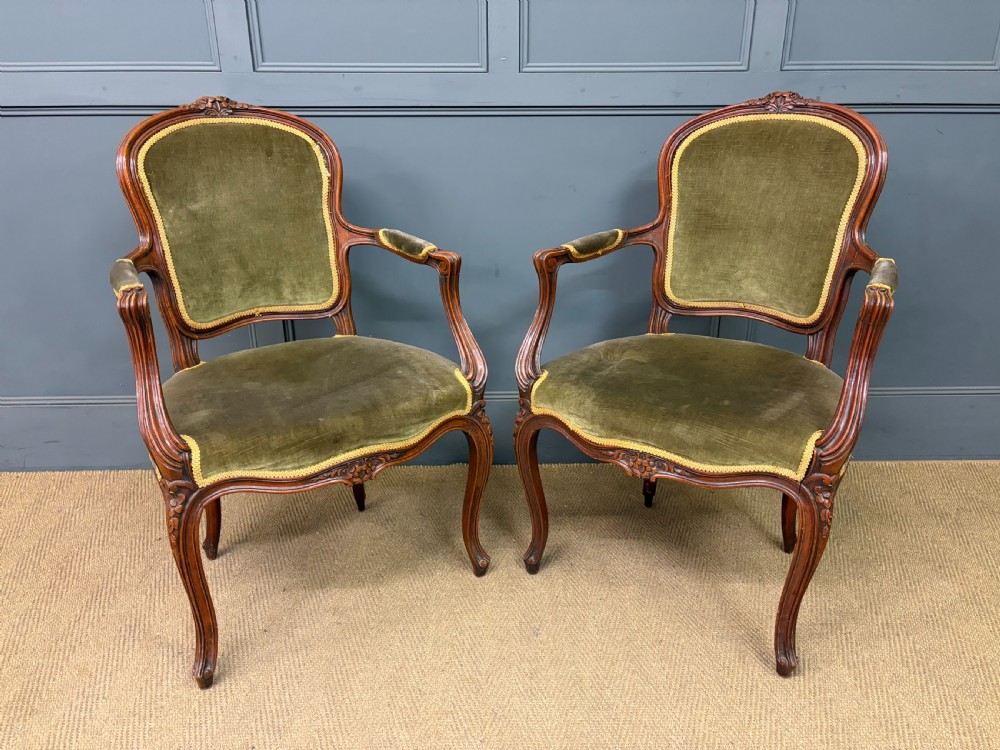 A pair of French carved mahogany fauteuil armchairs featuring cabriole legs and olive green velvet upholstery.