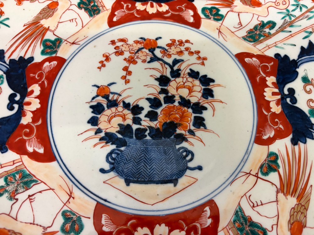 A circular 19th-century Japanese Imari porcelain charger decorated in cobalt blue, iron red, and gilt with paneled bird and floral motifs around a central vase design. View III