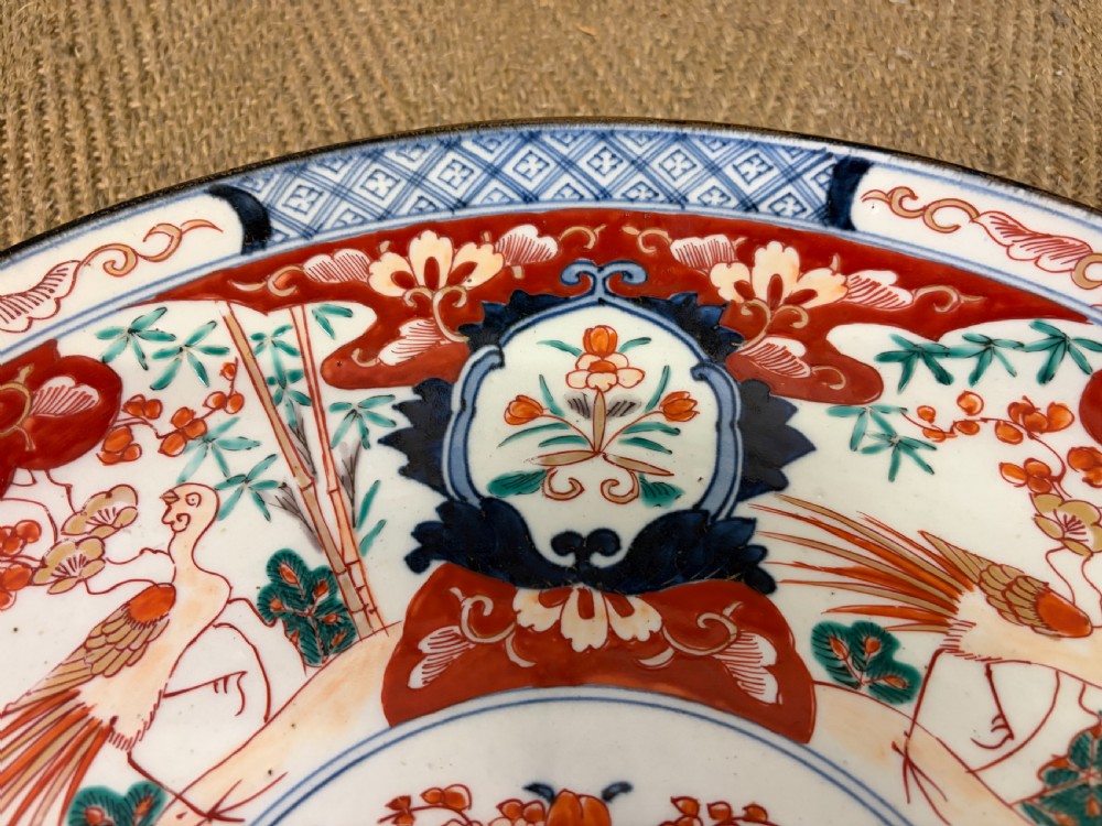 A circular 19th-century Japanese Imari porcelain charger decorated in cobalt blue, iron red, and gilt with paneled bird and floral motifs around a central vase design. View IV