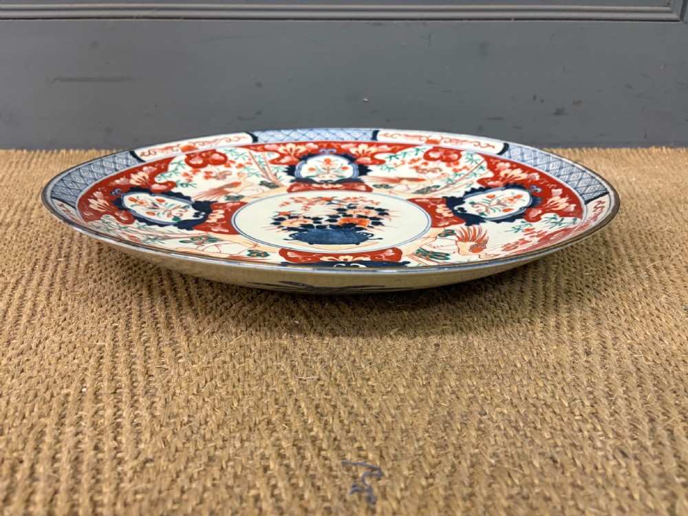 A circular 19th-century Japanese Imari porcelain charger decorated in cobalt blue, iron red, and gilt with paneled bird and floral motifs around a central vase design. View VII