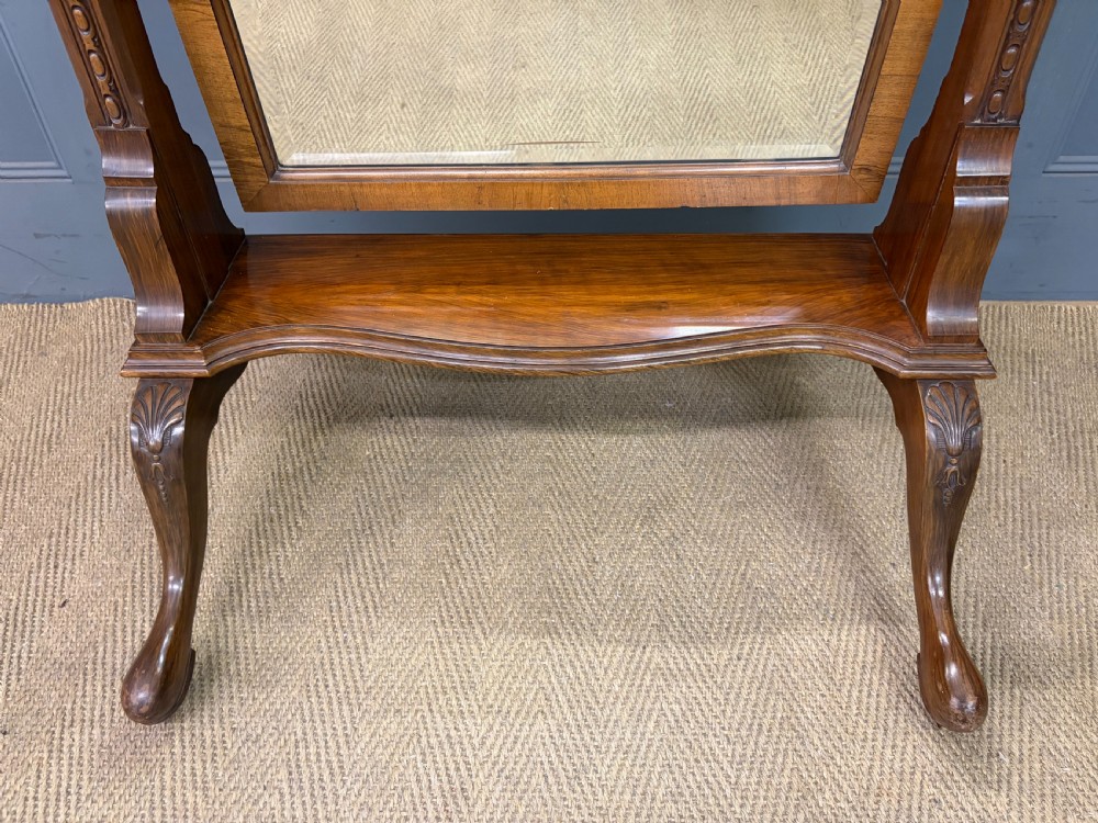 A Queen Anne style walnut cheval mirror with an arched frame, carved shell motif, finial posts, and cabriole legs. View V