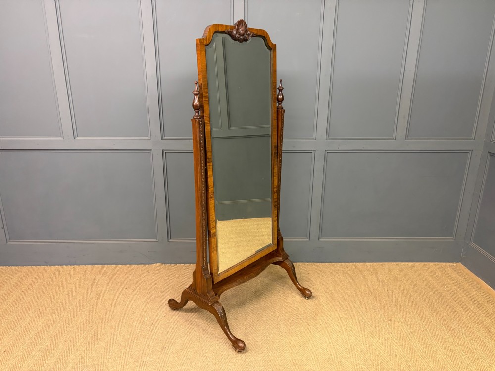 A Queen Anne style walnut cheval mirror with an arched frame, carved shell motif, finial posts, and cabriole legs. View VI