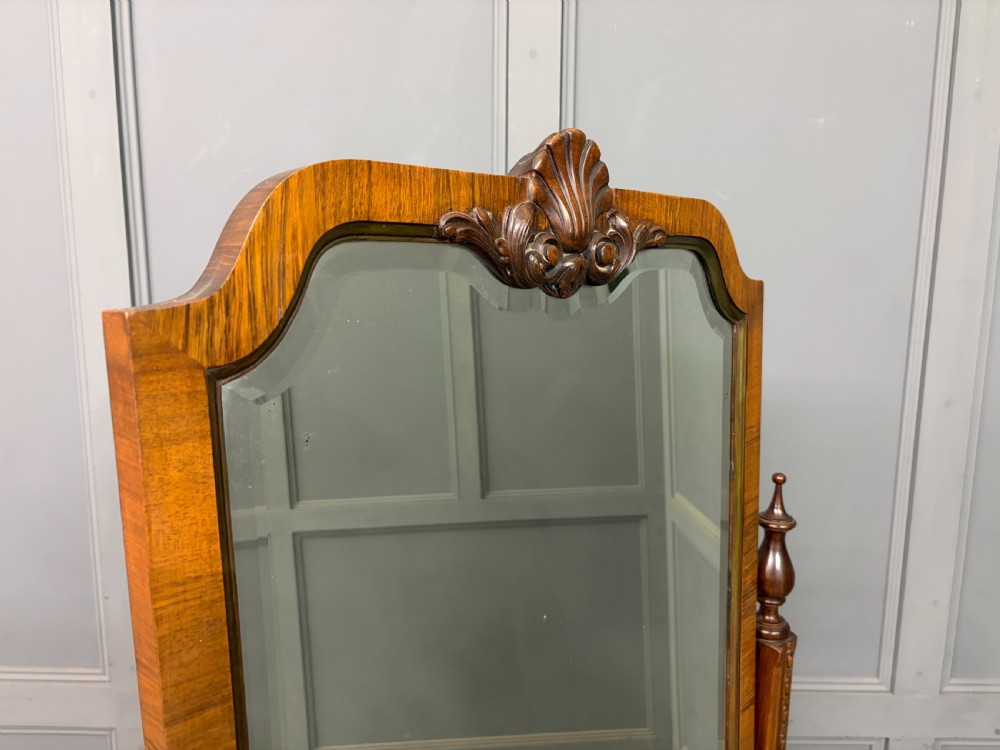 A Queen Anne style walnut cheval mirror with an arched frame, carved shell motif, finial posts, and cabriole legs. View VIII