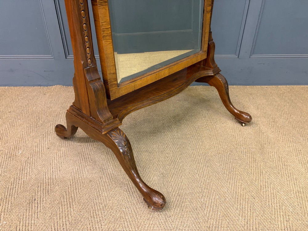 A Queen Anne style walnut cheval mirror with an arched frame, carved shell motif, finial posts, and cabriole legs. View IX