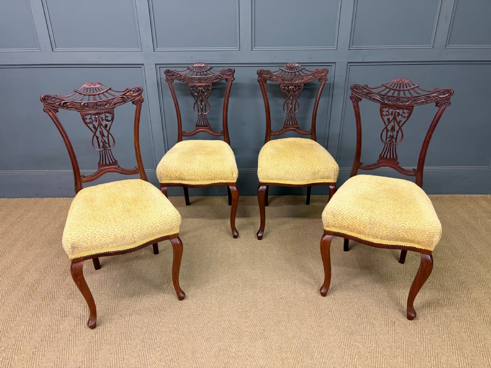 A seven-piece Victorian mahogany salon suite comprising a carved settee, two armchairs, and four side chairs, all upholstered in yellow patterned fabric. View II
