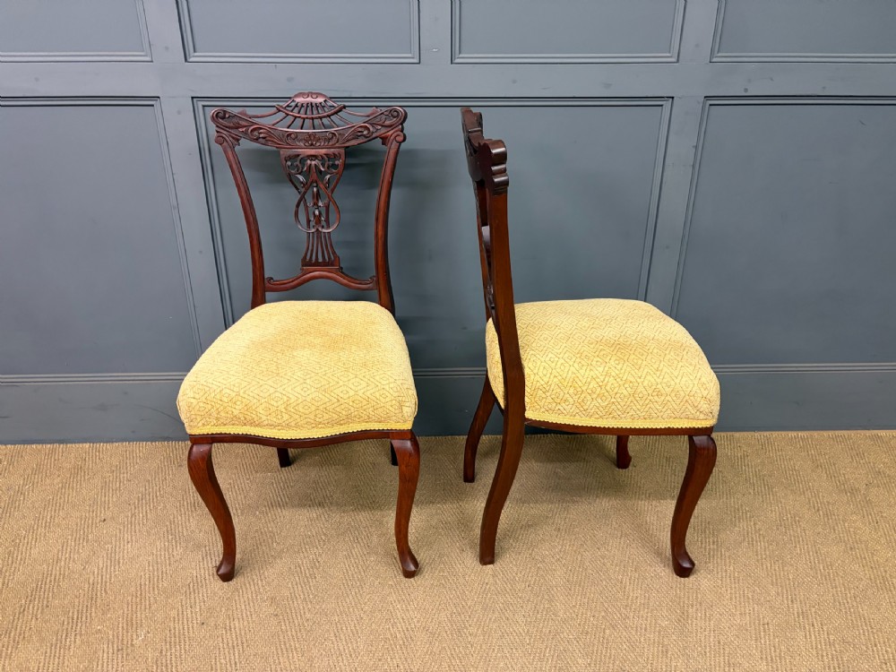 A seven-piece Victorian mahogany salon suite comprising a carved settee, two armchairs, and four side chairs, all upholstered in yellow patterned fabric. View III